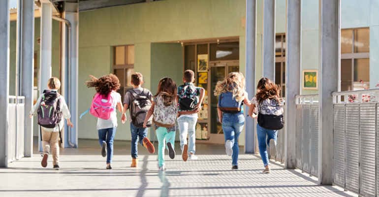 Bambini corrono corrono per entrare in classe nel corridoio della scuola