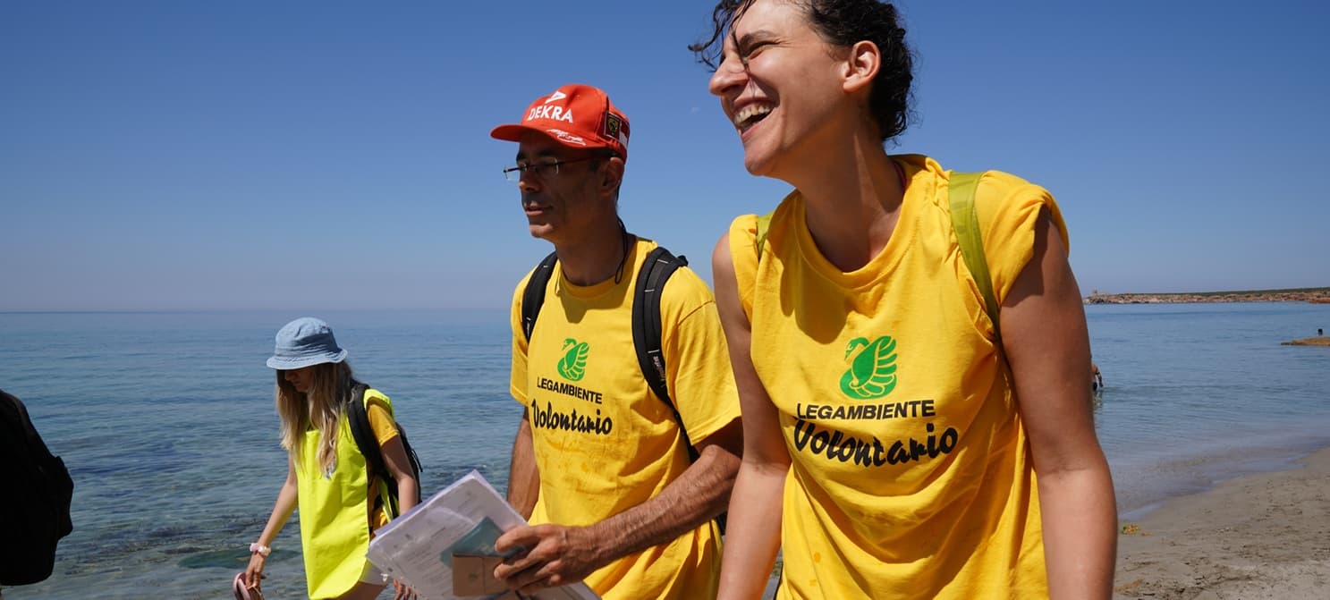 2 volontari con la maglietta di Legambiente passeggiano lungo la battigia