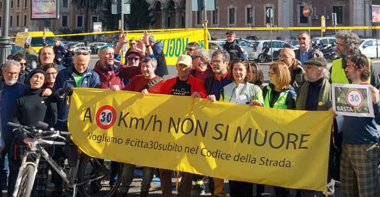 Persone manifestano in piazza con striscione "a 30km/h non si muore"